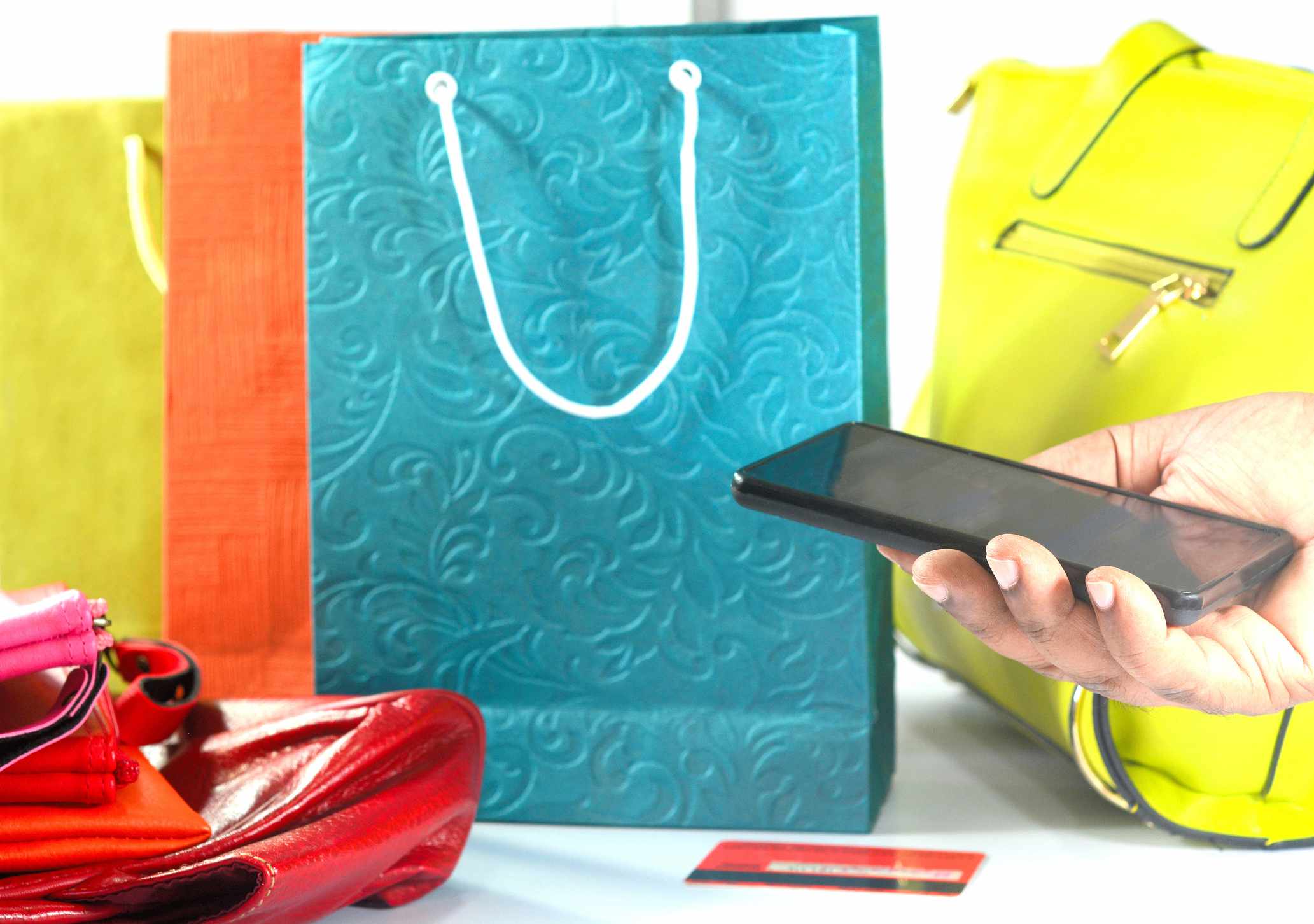 Concept van online winkelen met boodschappentassen, handtassen en portemonnees gekocht met behulp van slimme telefoon.
