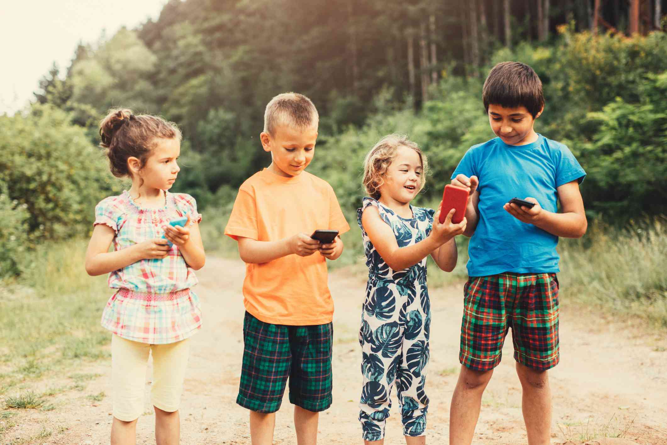 Vier kinderen die buiten smartphones gebruiken.