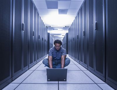 Man met computer in loopbrug tussen servers