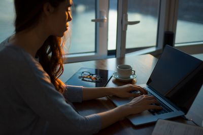 Een vrouw die een laptop gebruikt aan een tafel