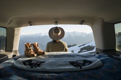 Wandelaar zit in de auto voor besneeuwde bergen