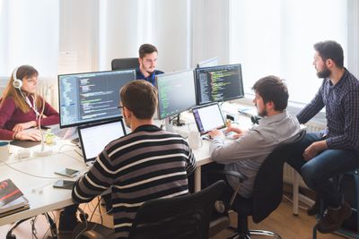 Softwareontwikkelingsteam dat op kantoor werkt met grote monitoren