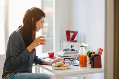 Zelfstandige freelancer die laptop gebruikt tijdens het ontbijt