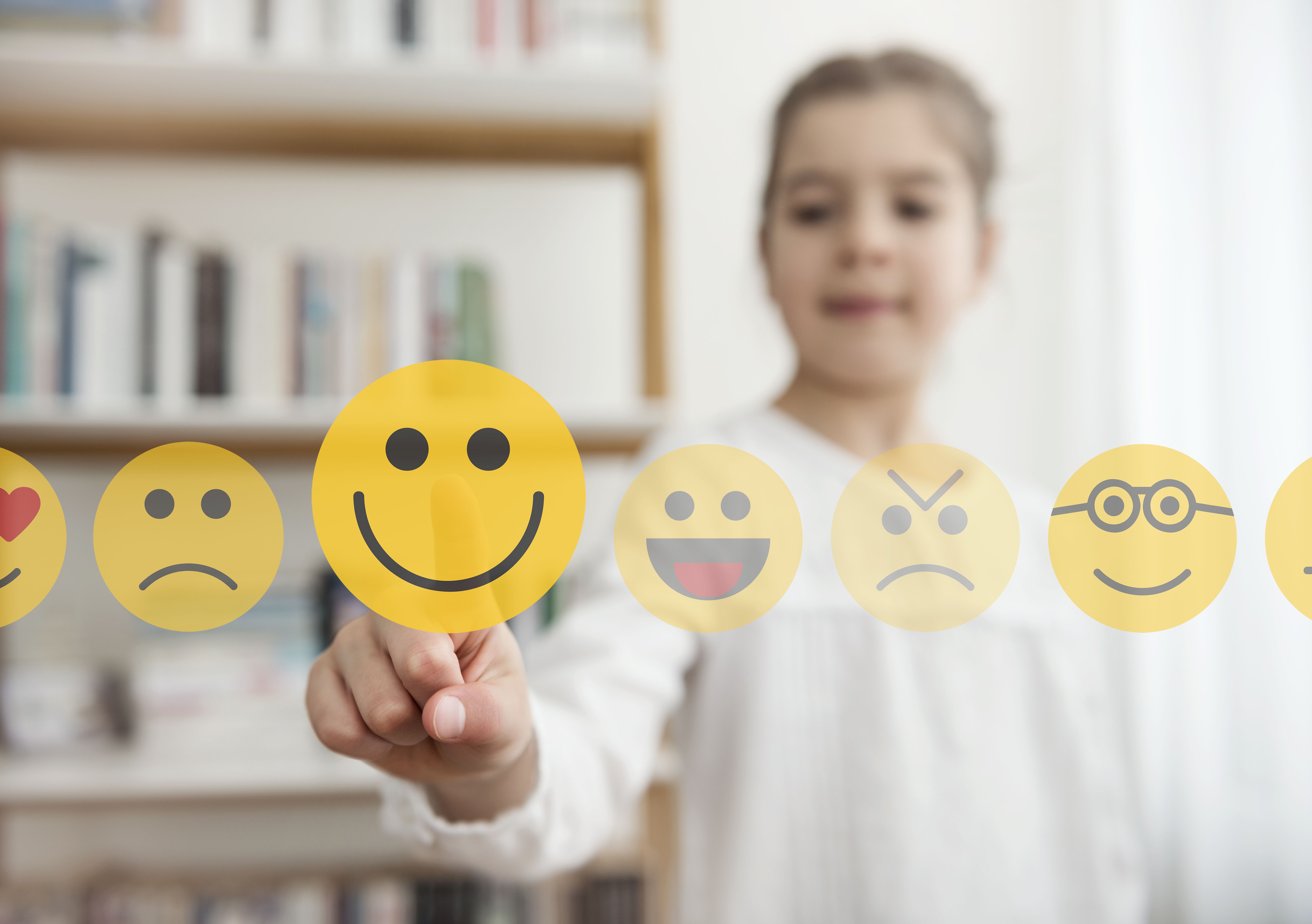 Klein meisje dat het smiley-emoji-pictogram op het aanraakscherm aanraakt