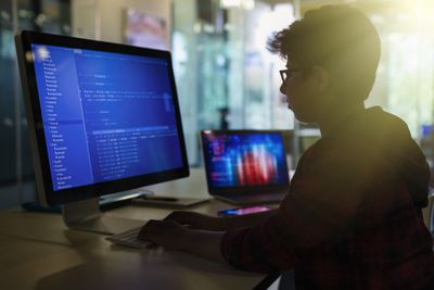 Jonge jongen student programmeren op computer in donkere klas