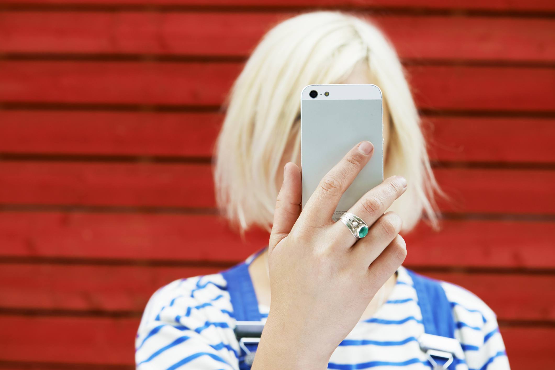 Vrouw houdt mobiele telefoon tegen haar gezicht