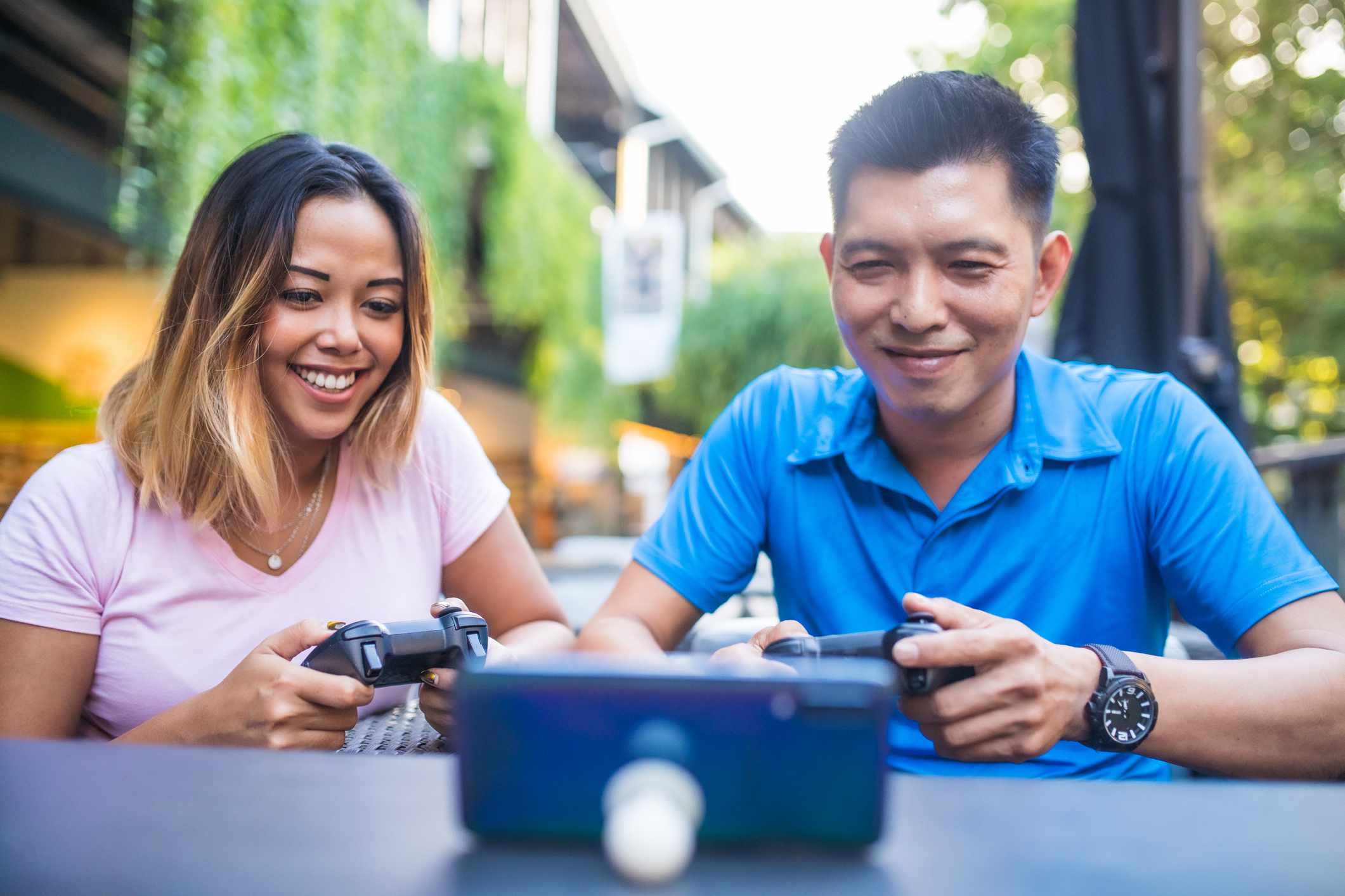Twee mensen spelen buiten een game op een smartphone met controllers.