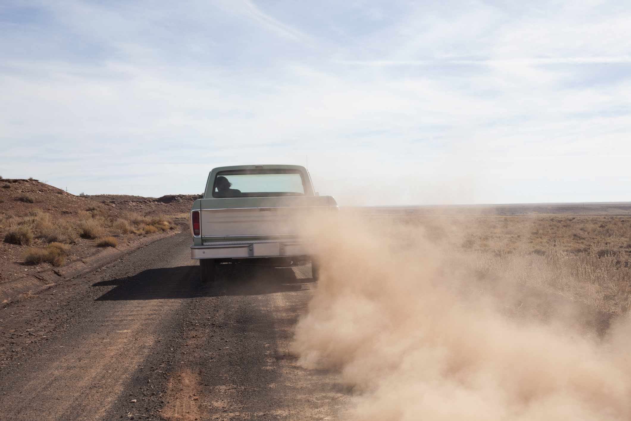 Een ouder model pick-up op een onverharde weg.