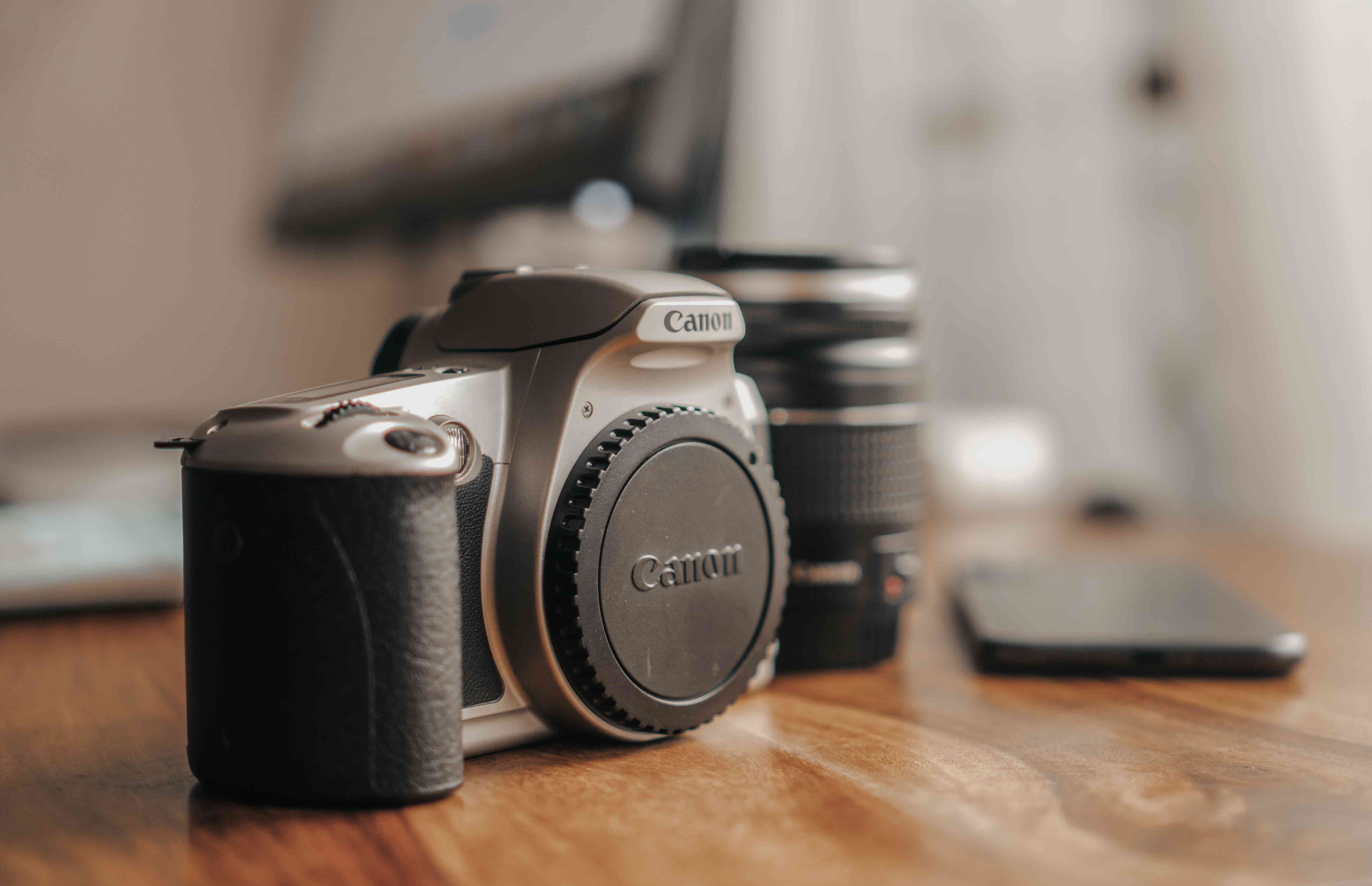 Een Canon film SLR camera met een vrijstaande lens erachter.
