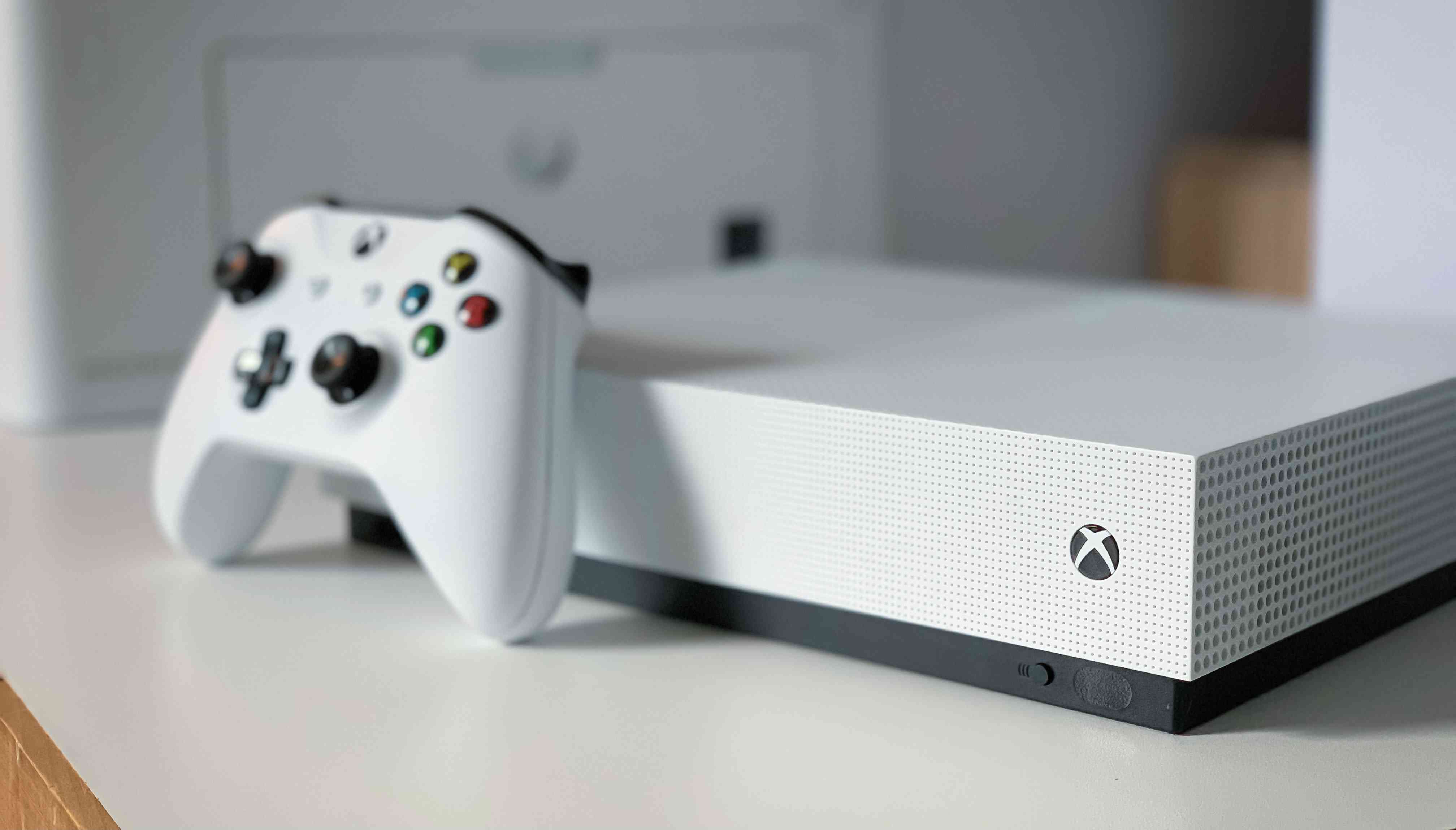 Witte Xbox One-console met een witte controller ertegenaan geleund.