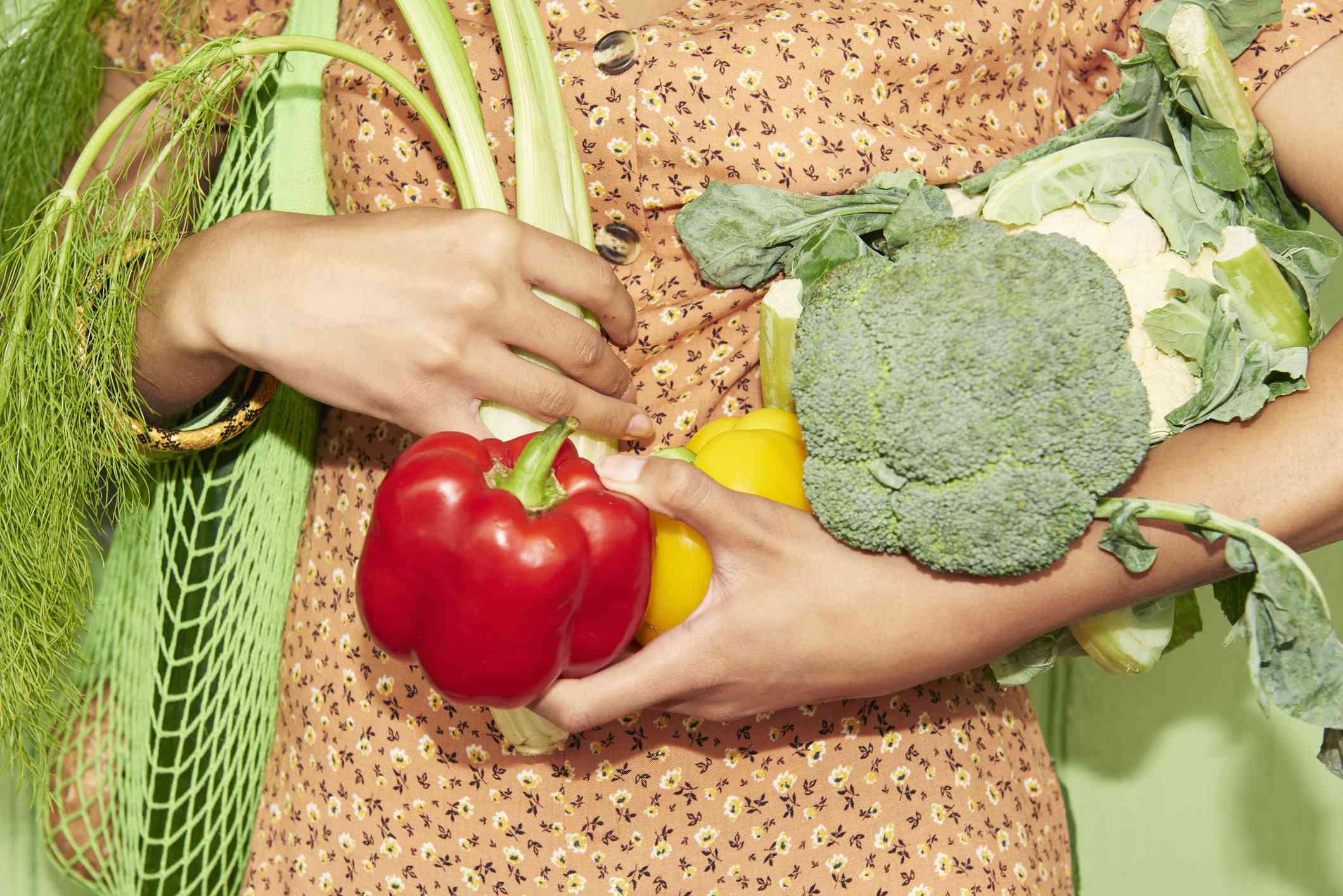 Close-up van iemand die een armvol verse groenten vasthoudt.
