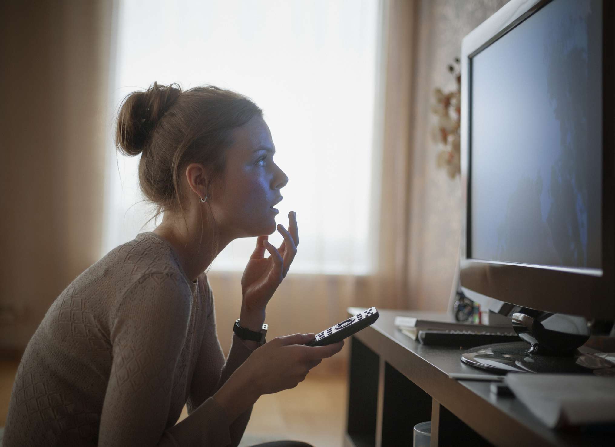 jonge vrouw kijkt in spanning naar tv
