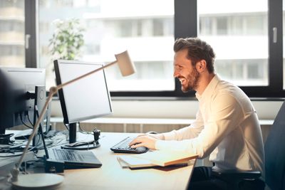 Gelukkig man aan het werk op desktopcomputer