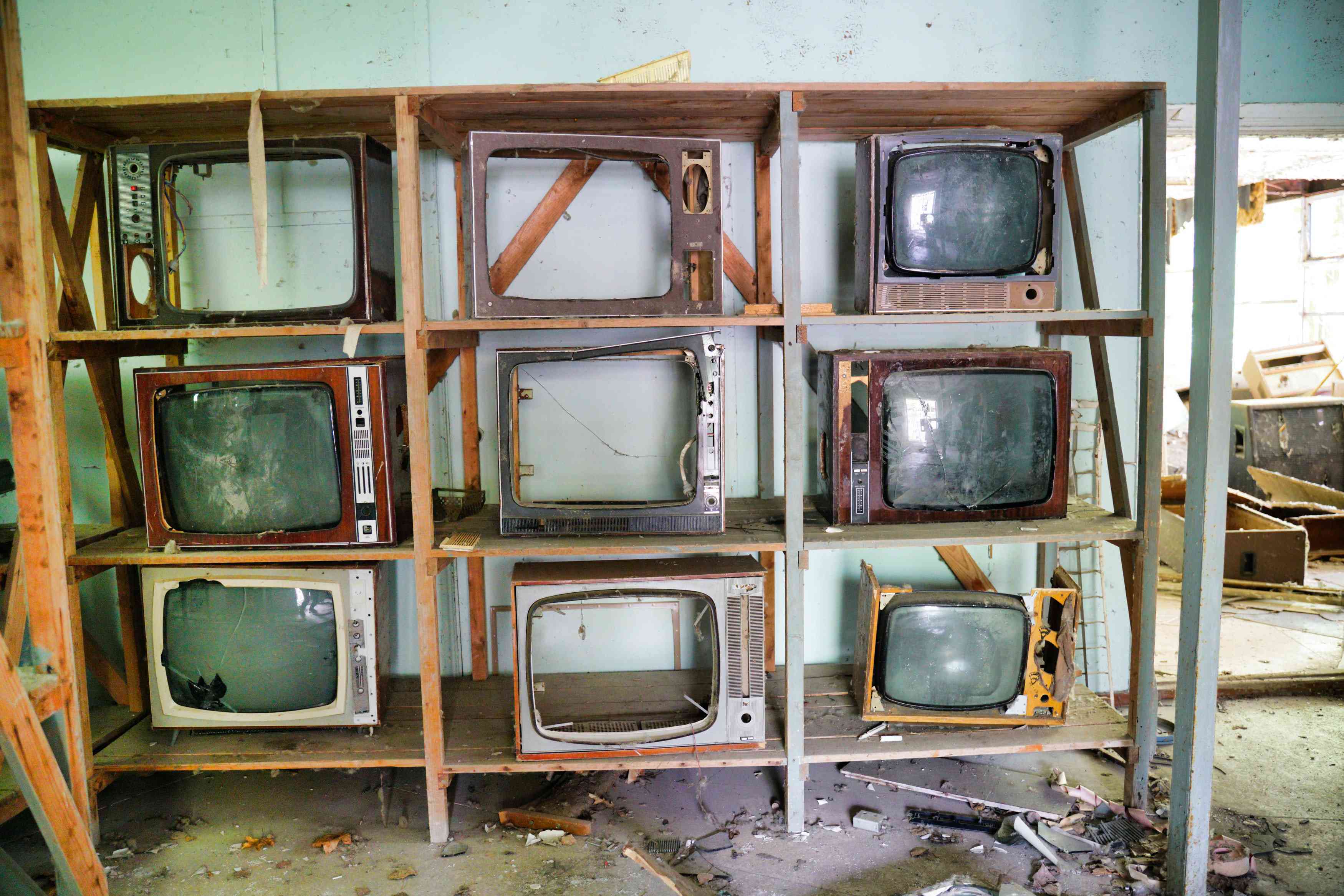 Gebroken vintage televisietoestellen op een plank in een verlaten gebouw. 