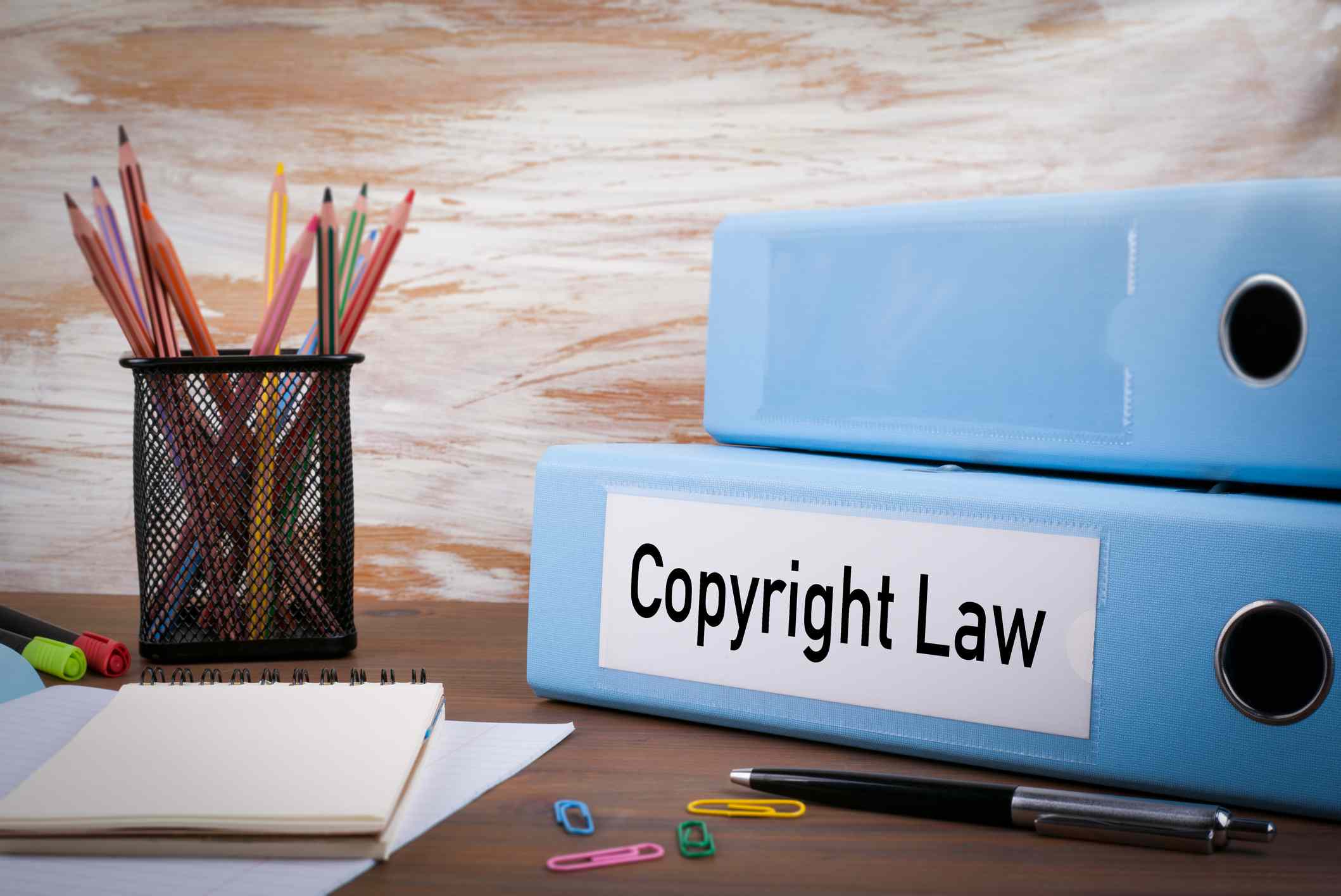 Een map met het label "Copyright Law" zittend op een bureau met blocnotes, paperclips en schrijfinstrumenten.