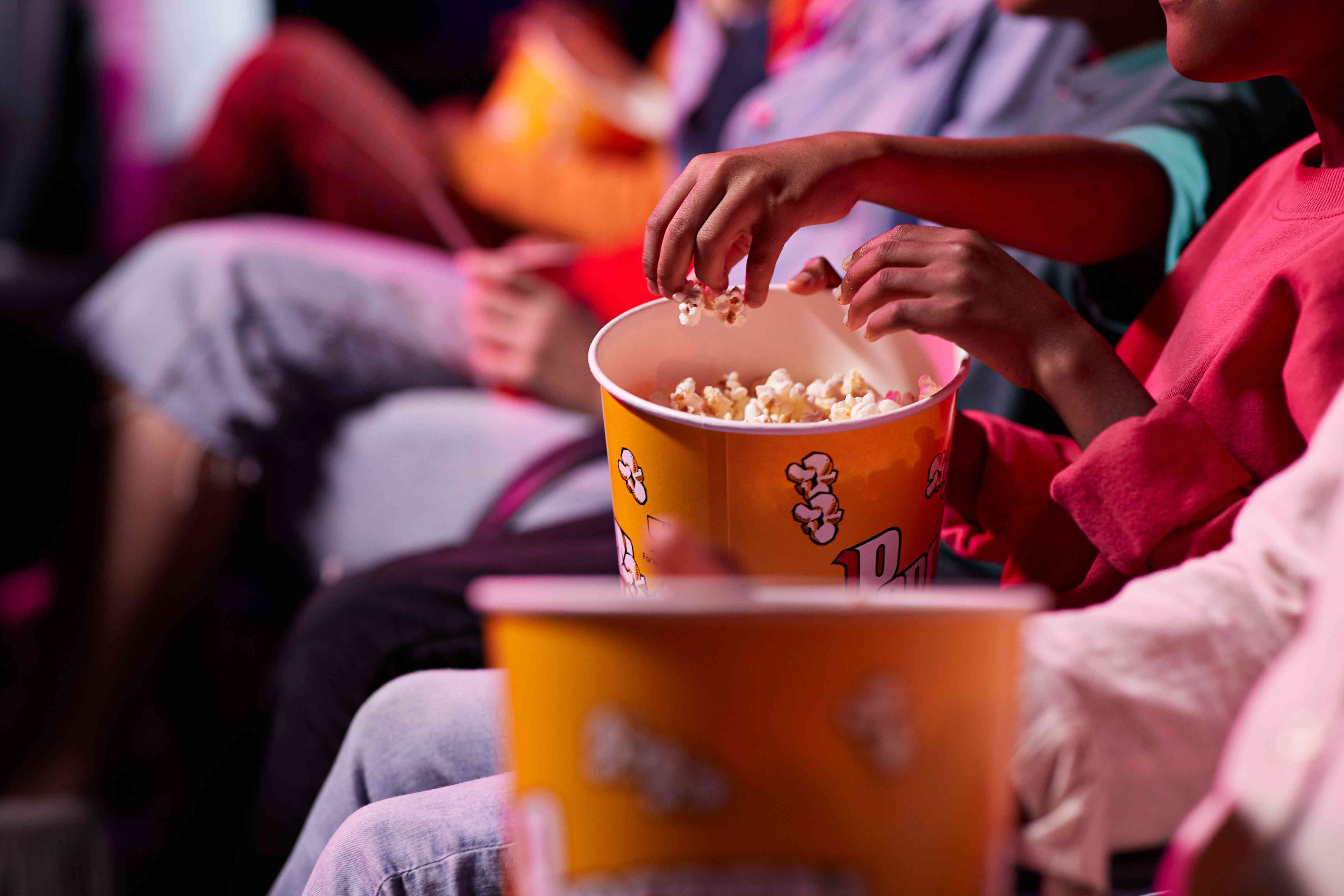 Buik van vrienden die popcorn delen terwijl ze in het theater zitten