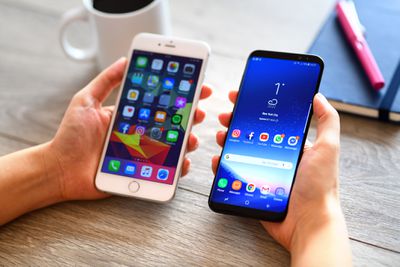 Een iPhone en Samsung-telefoon naast elkaar op een bureau