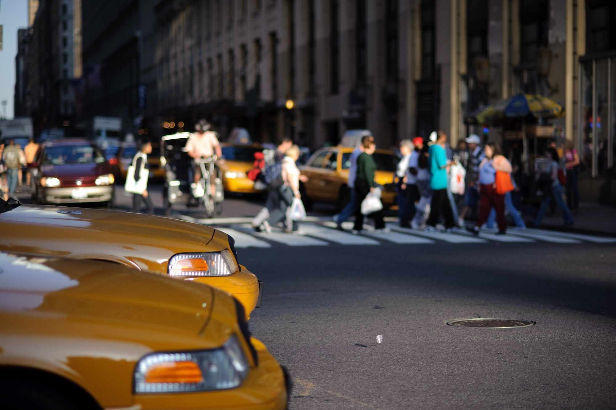 Paar taxi's wachten op een kruispunt terwijl mensen op de achtergrond de straat oversteken