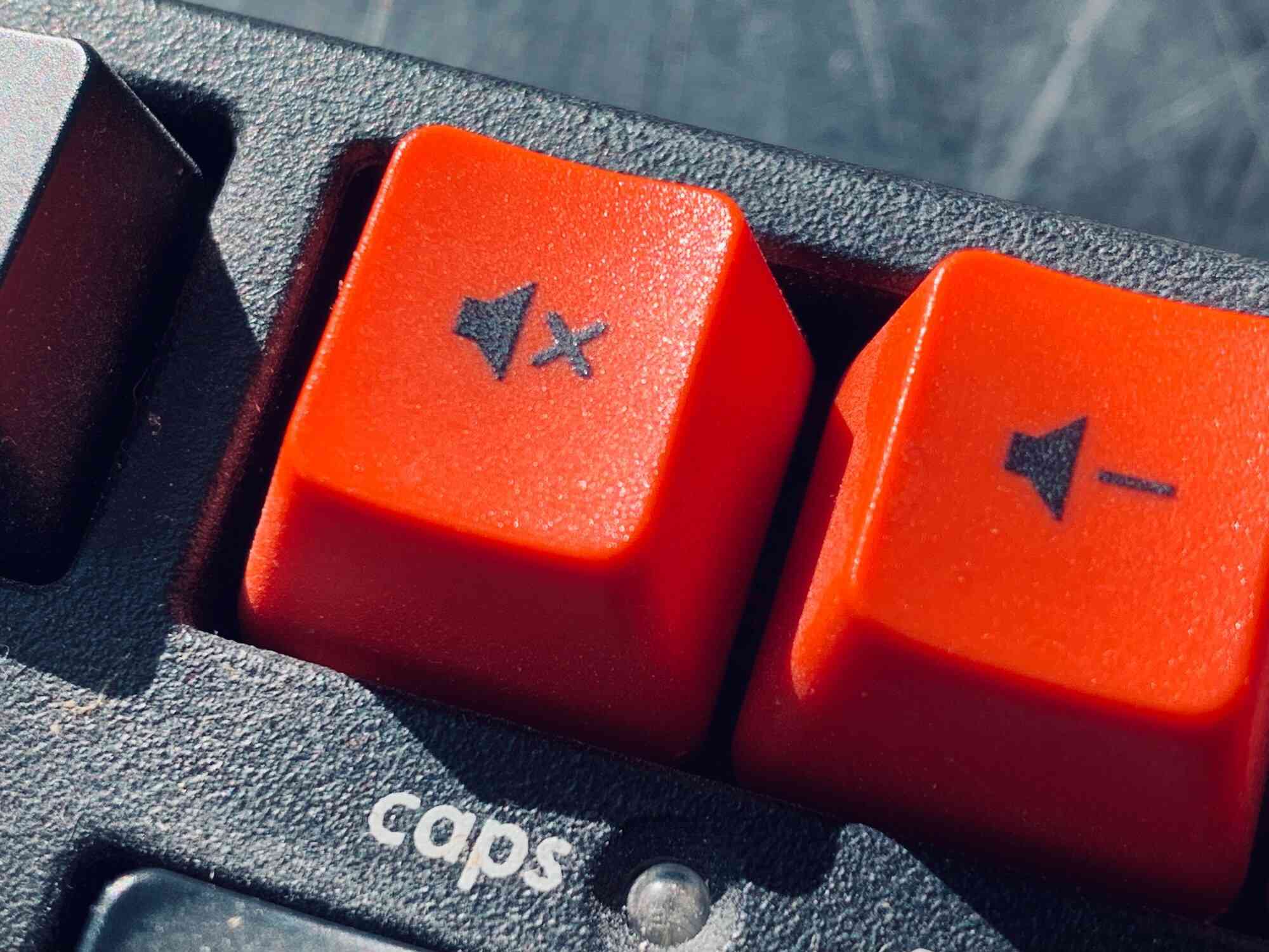 Close-up van de rode mute- en volume-omlaagtoetsen van een mechanisch toetsenbord