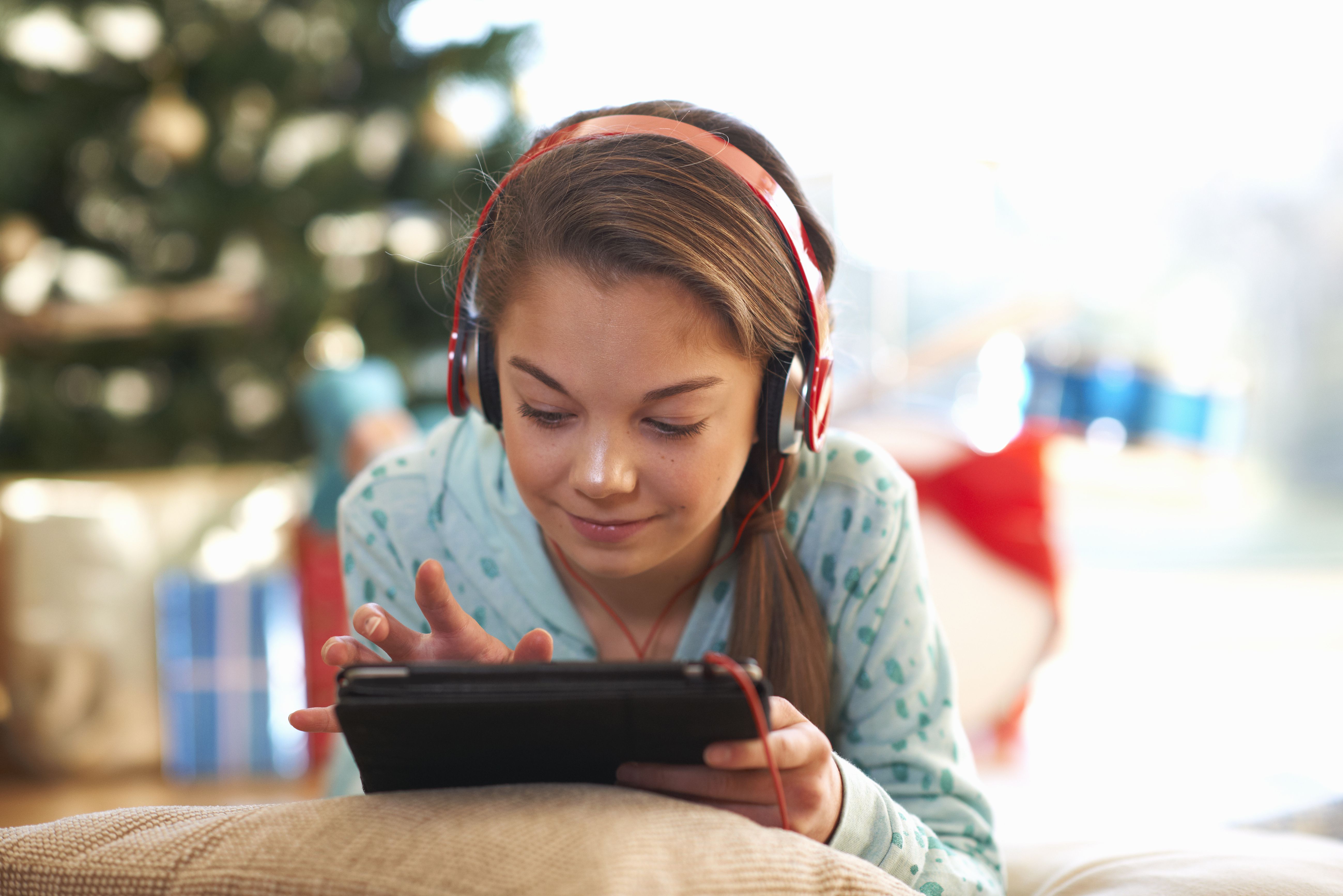 Meisje liggend op de vloer van de woonkamer met behulp van digitale tablet touchscreen met Kerstmis