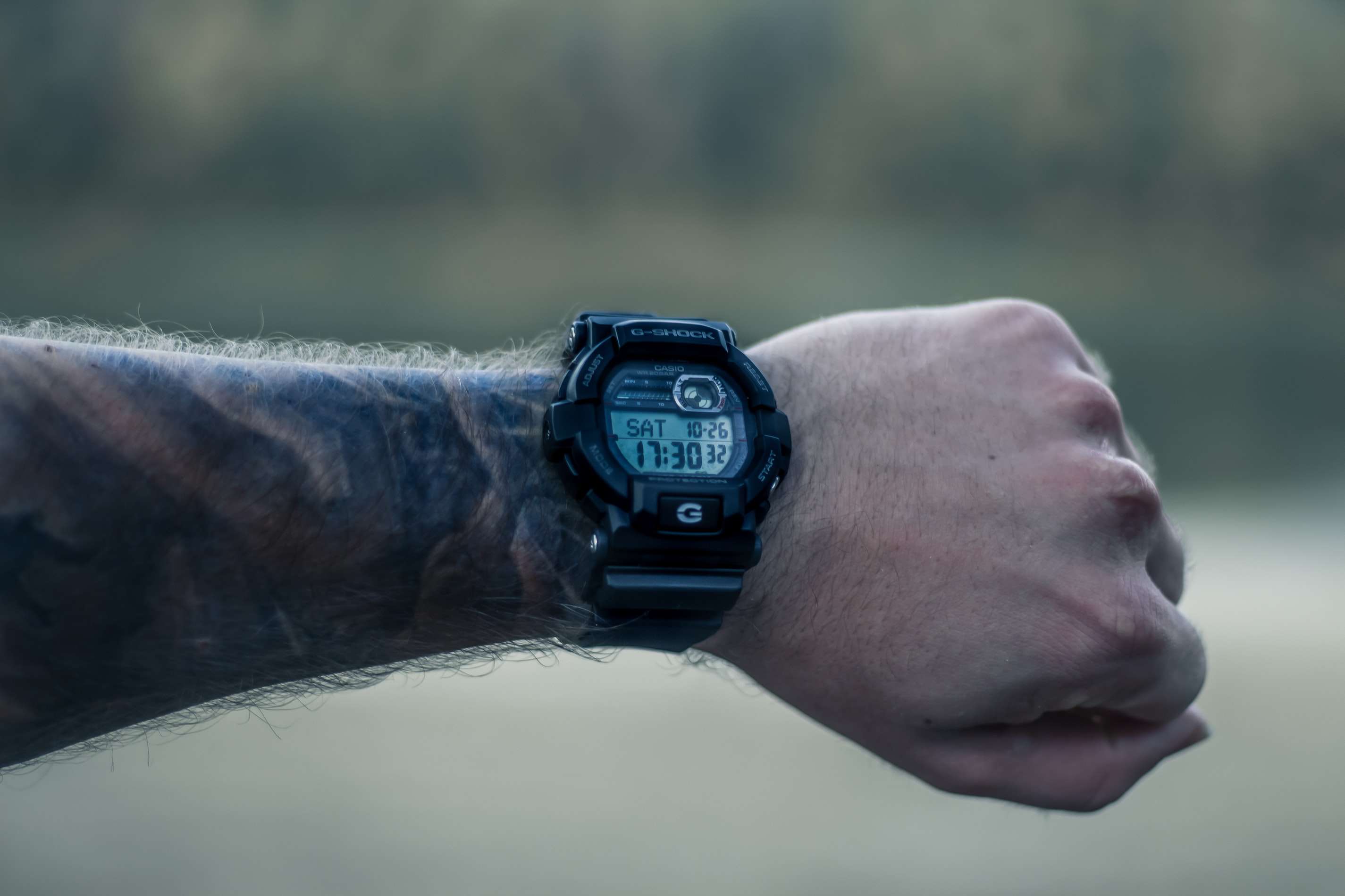 Persoon met tatoeages die een Casio G-Shock horloge draagt