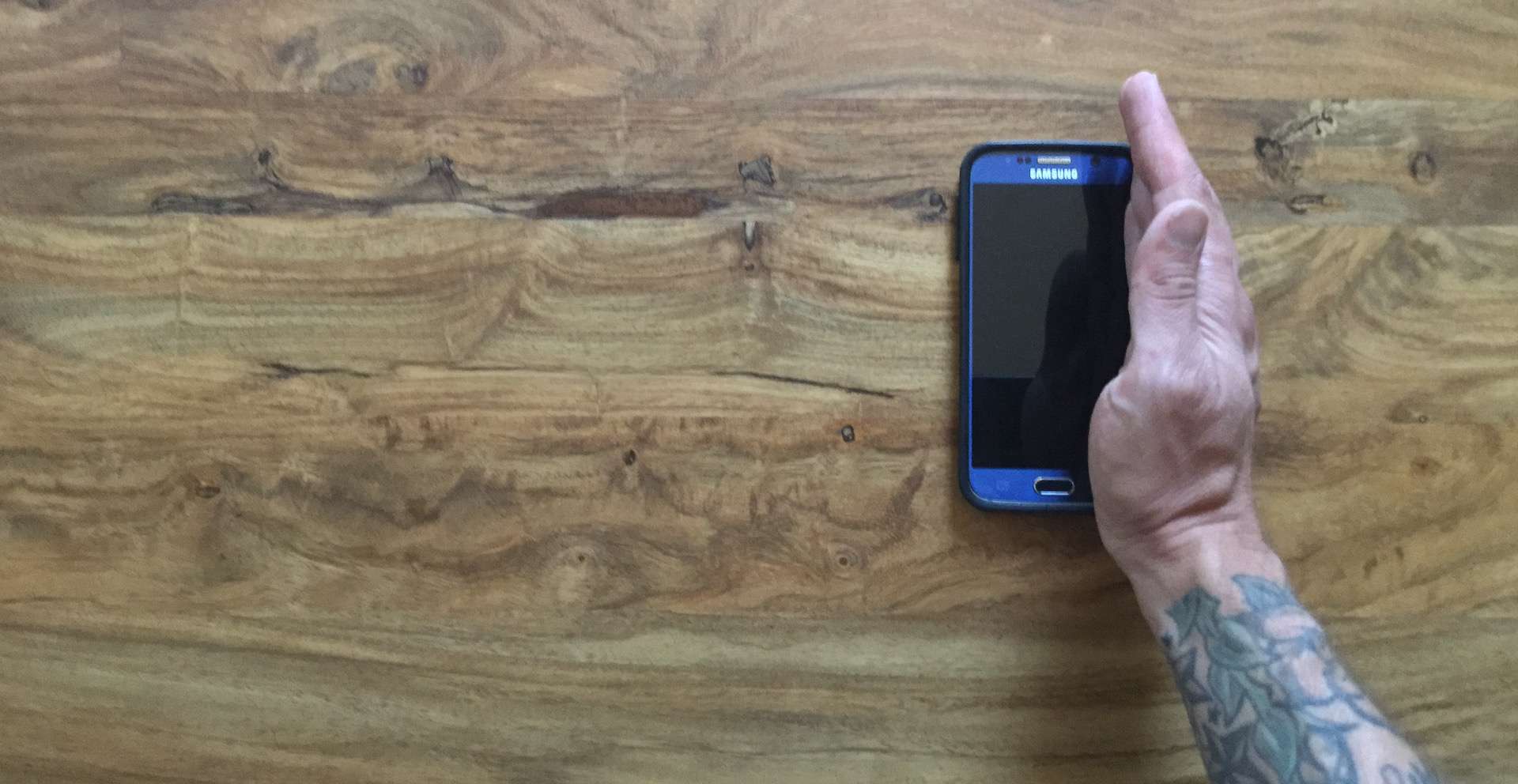 De hand van een man is verticaal op de rand van een Samsung S6.