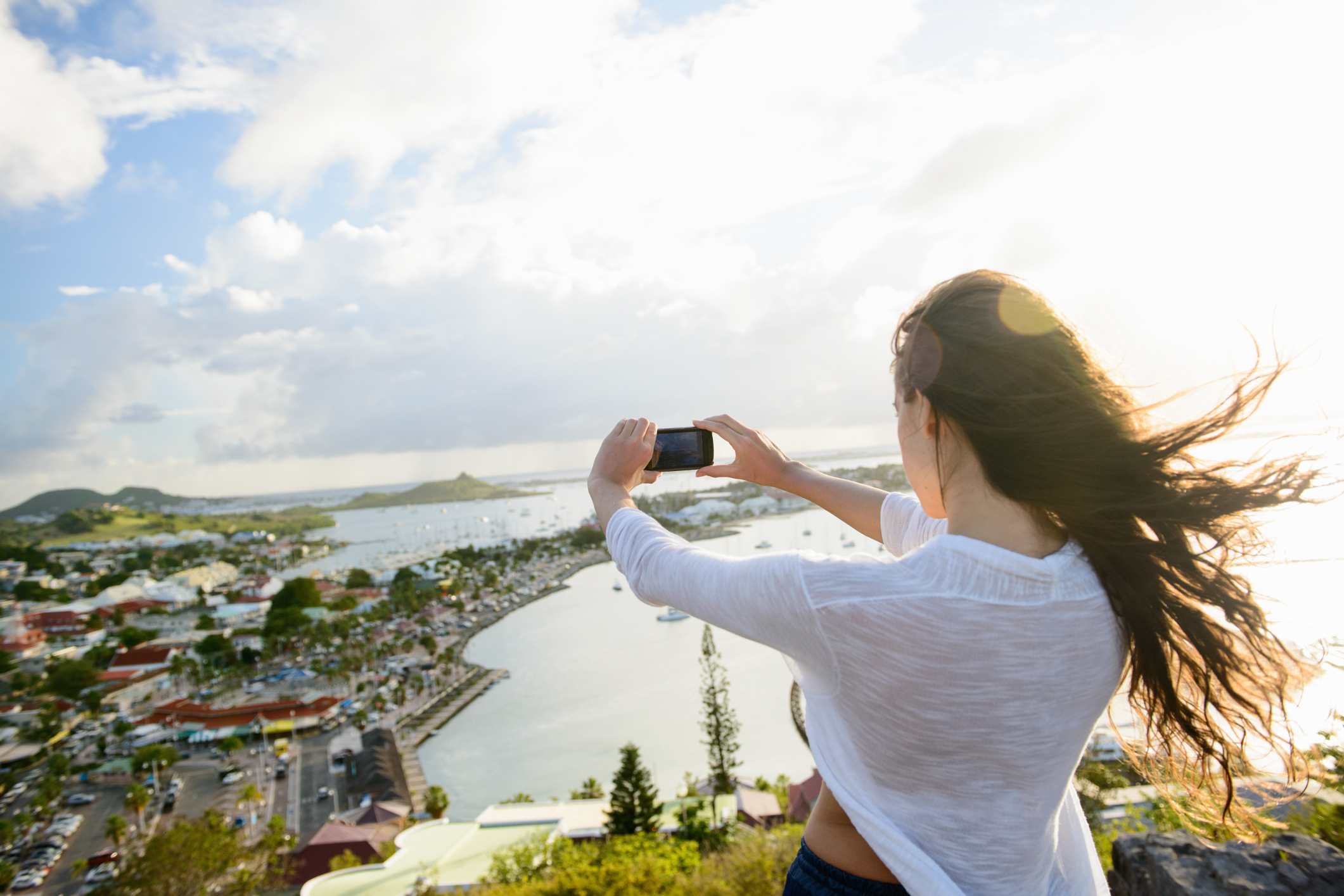 Persoon die selfie maakt bovenop een heuvel bij een baai