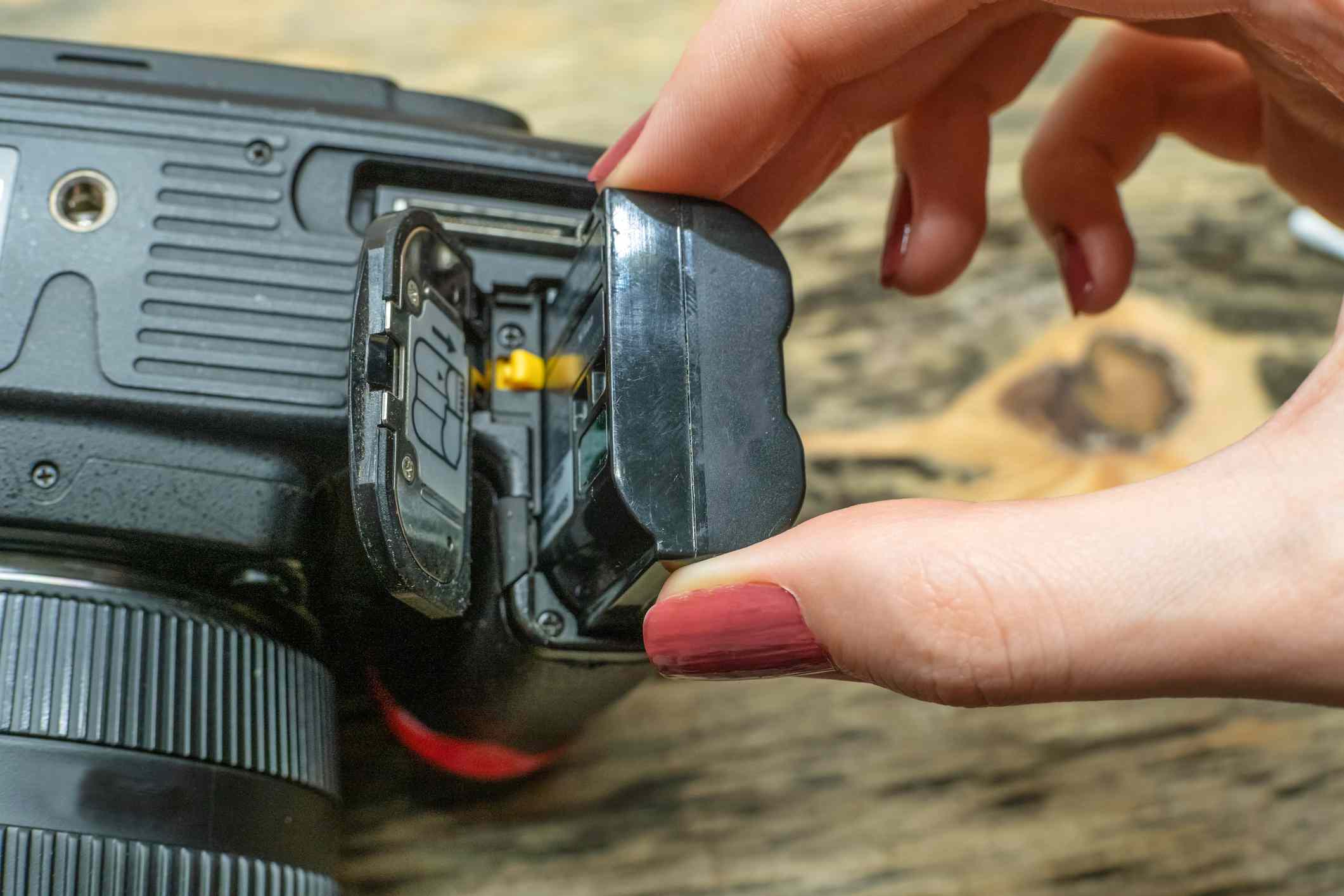 Een fotograaf verwisselt de batterij in haar spiegelreflexcamera