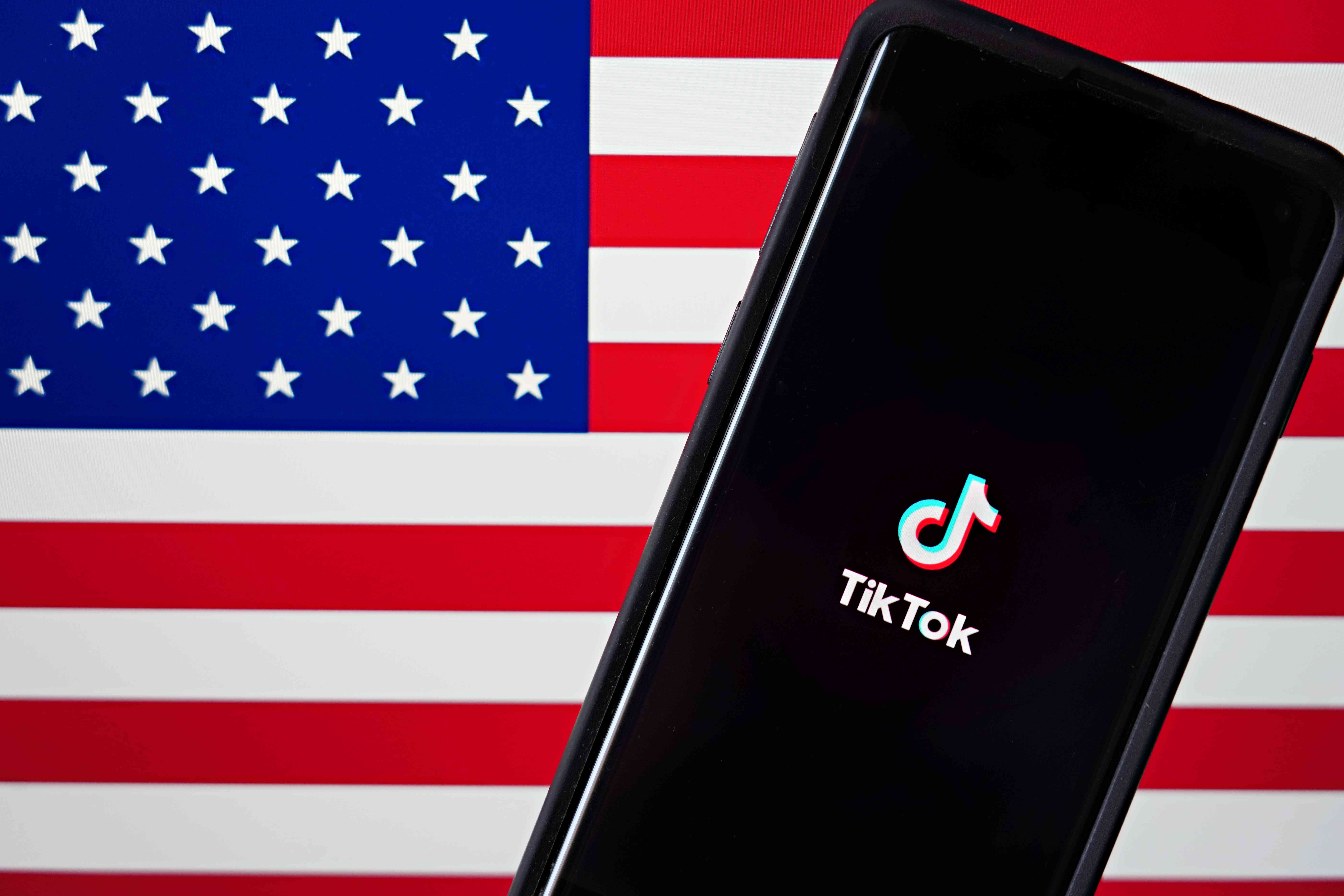 Een mobiele telefoon met de TikTok-app wordt weergegeven naast de Amerikaanse vlag