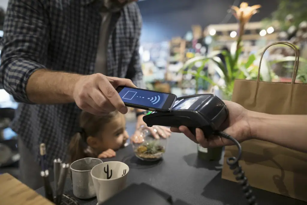 close up father and daughter paying with smart phone contactless payment at plant shop counter 697537221 5b2d60593037130036fa61c0