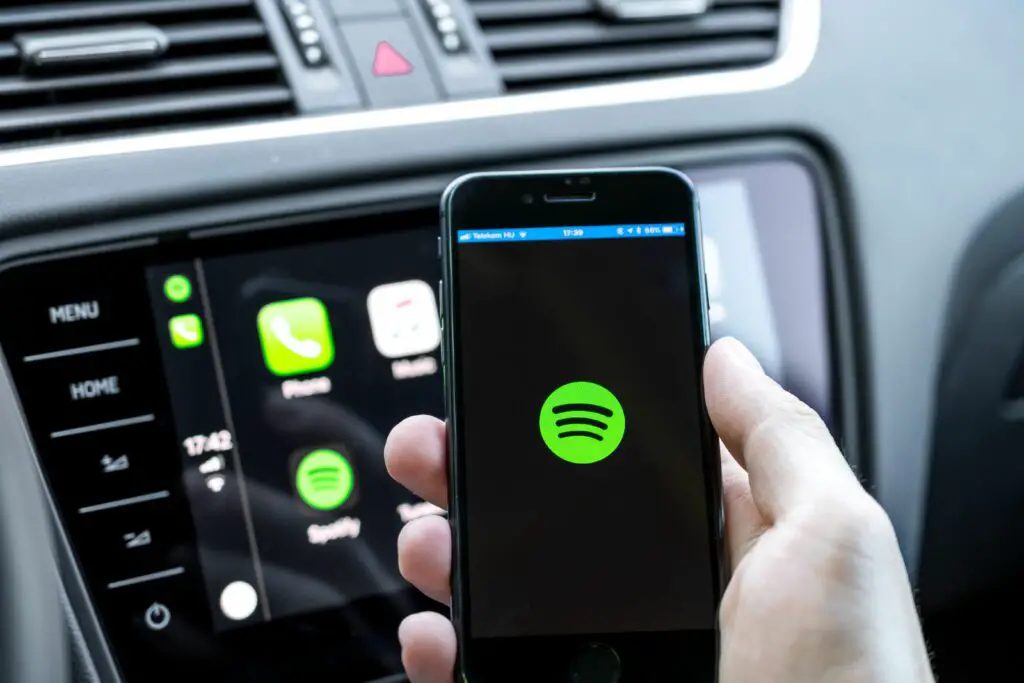 male hands holding a smartphone that is connecting to the car s computer running the popular music streaming service 998425776 5ba049bb46e0fb00509a1fb3