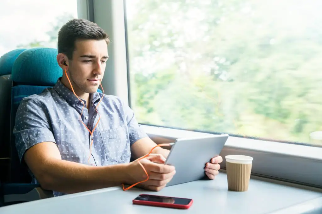 man with tablet and headphones on train 629639549 59c3f06422fa3a00118b0616