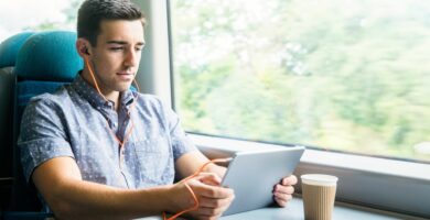 man with tablet and headphones on train 629639549 59c3f06422fa3a00118b0616