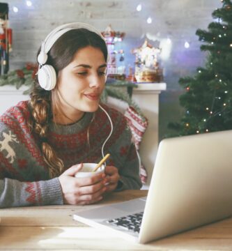 woman with cup of coffee using laptop and headphones at christmas time 681904577 59babded519de20010ea535e