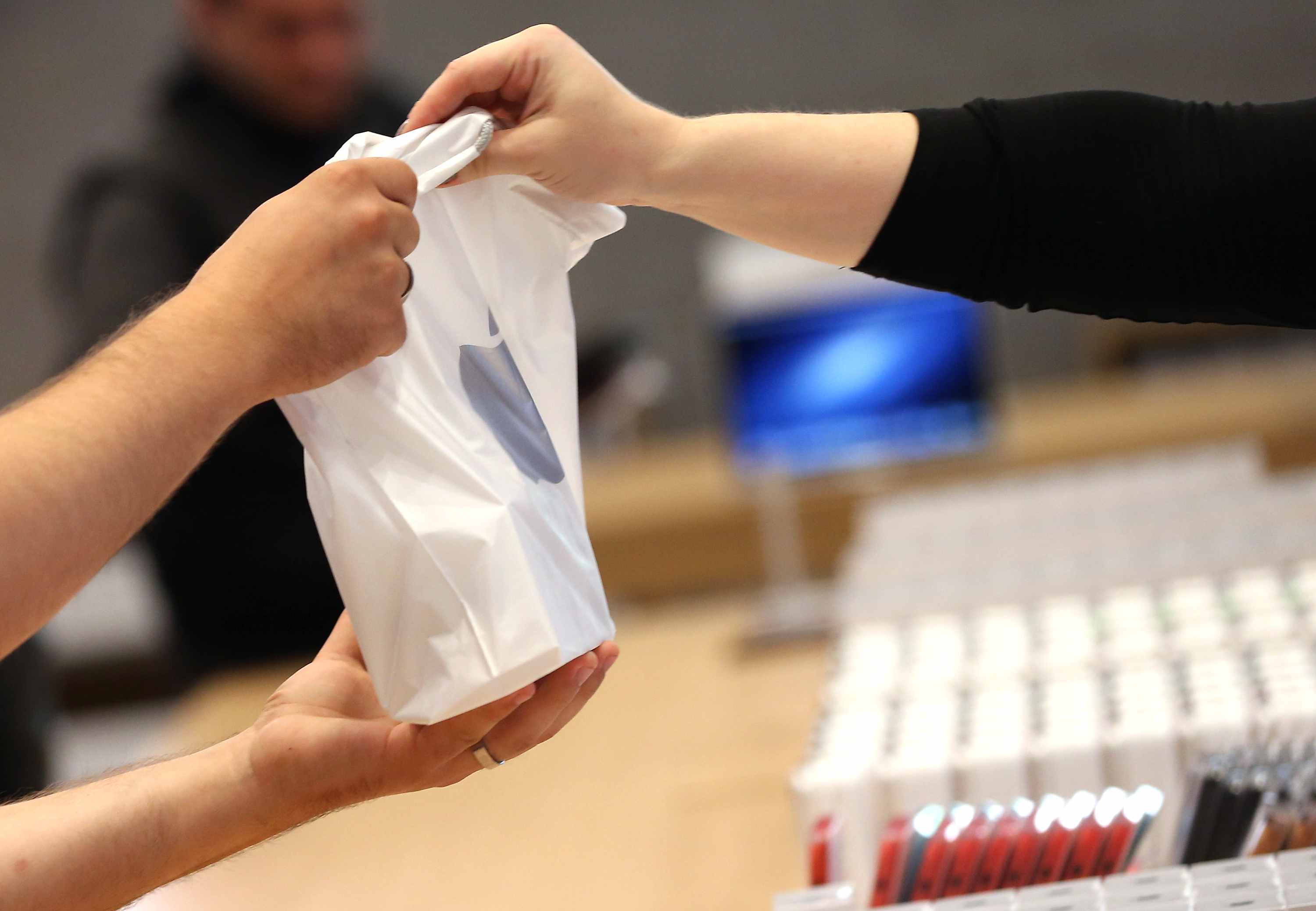 Sluit de handen van werknemers en klanten en een tas tijdens een aankoop bij een Apple Store.
