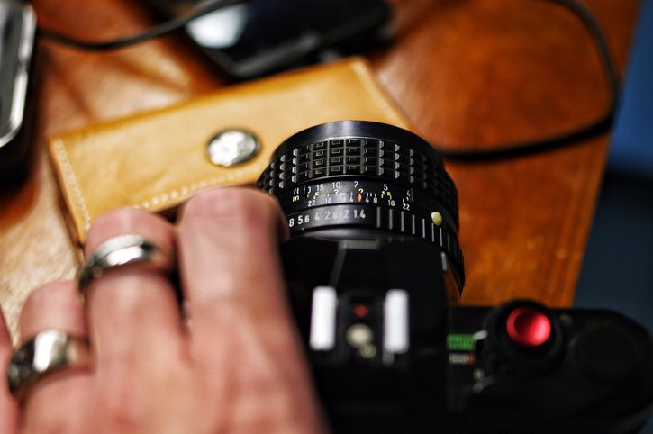 Een hand houdt een camera vast met de lens en scherpstelring prominent weergegeven