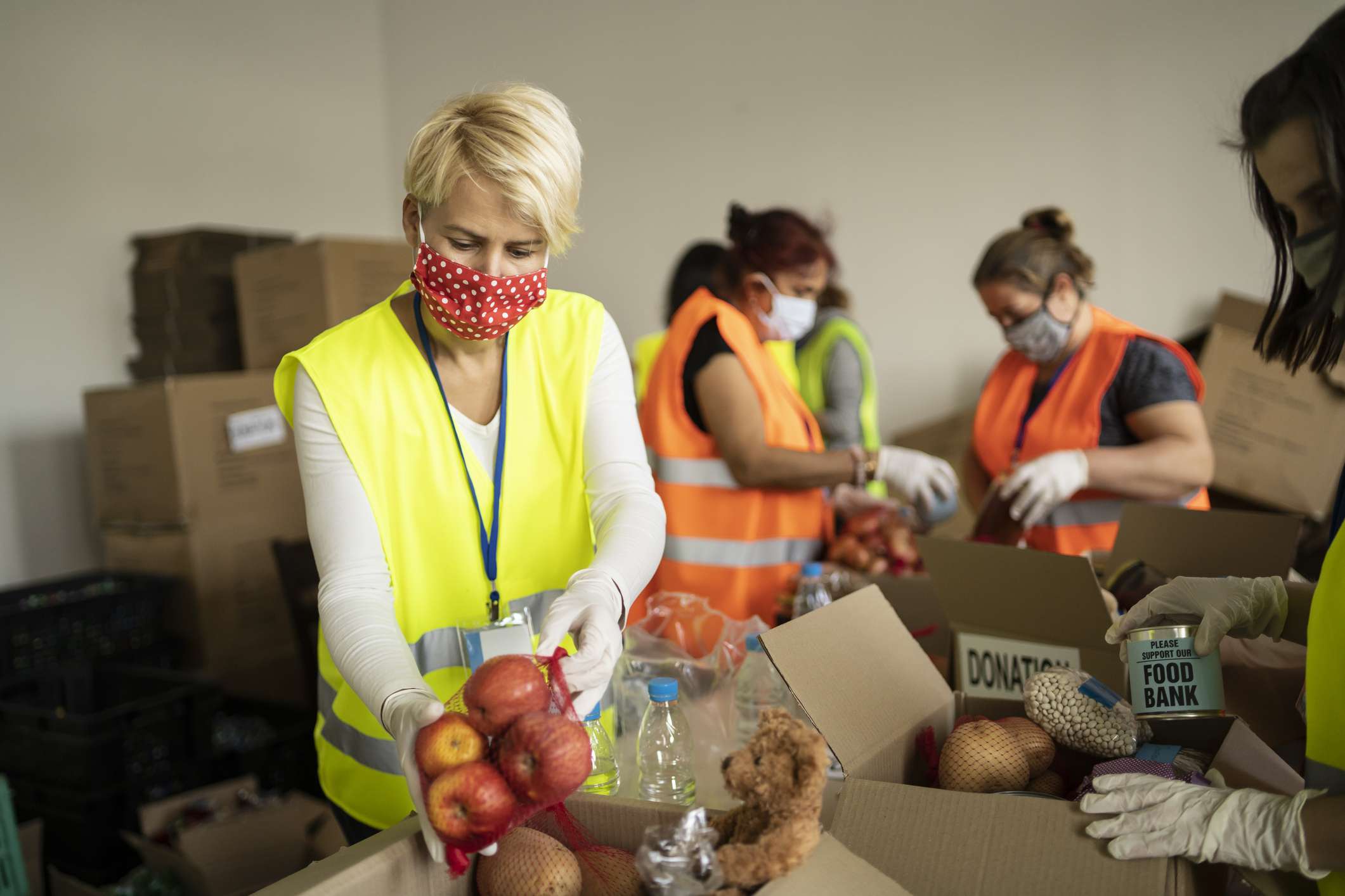 Mensen die beschermende maskers en handschoenen dragen die in een voedselbank werken.
