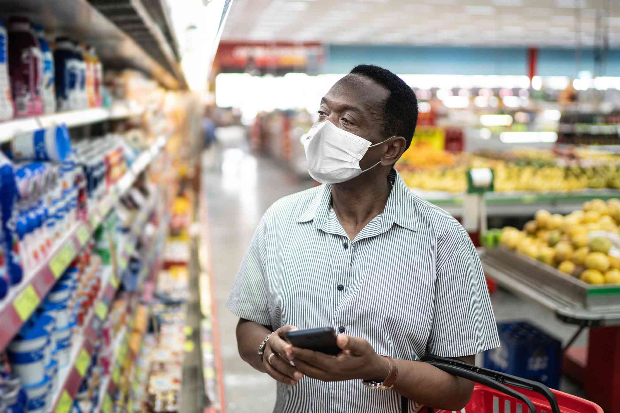 Iemand die een smartphone gebruikt tijdens het winkelen in een supermarkt. 