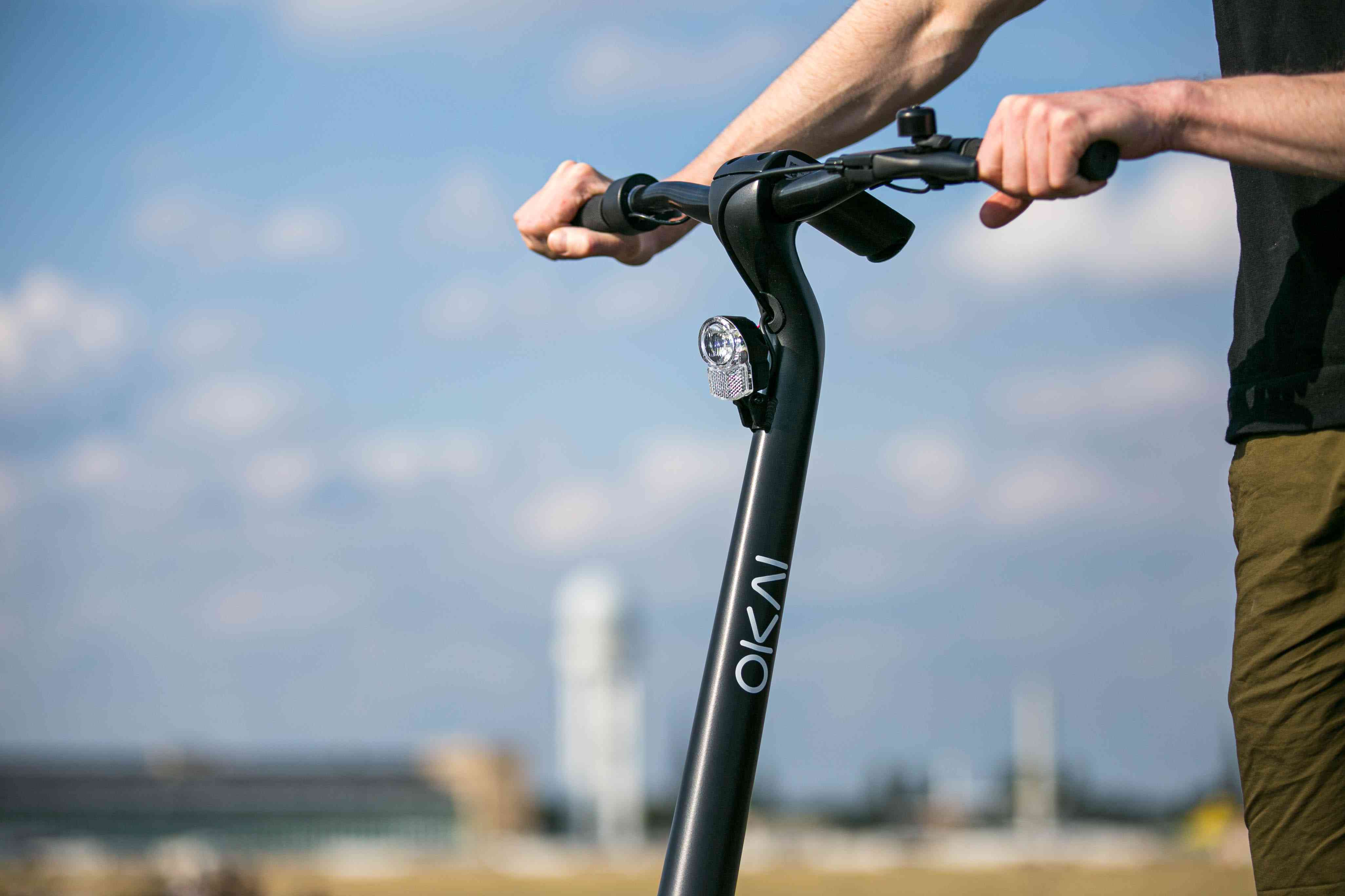 Close-up van iemand die zich vasthoudt aan het stuur van een elektrische scooter.