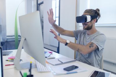 Computerprogrammeur die virtual reality-simulatorbril programmeert op de computer op kantoor