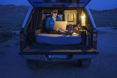 Camper die stroomomvormer gebruikt om laptop te gebruiken