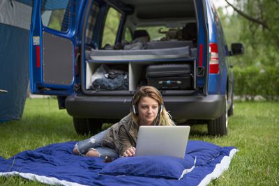 vrouw die auto-energie gebruikt om laptop op te laden tijdens kampeertrip
