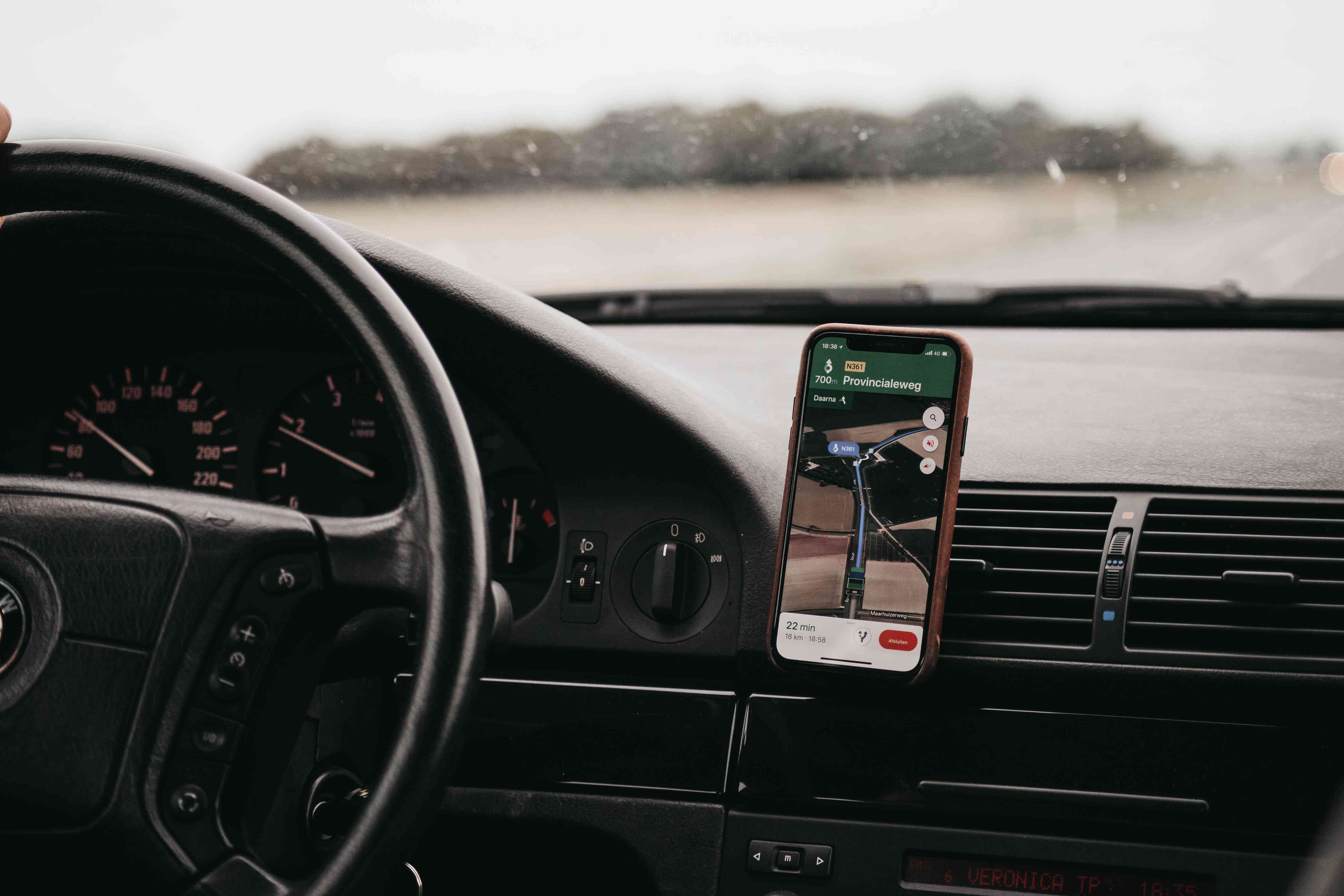 Een smartphone gemonteerd op een ventilatierooster van een auto met daarop een kaarttoepassing. 