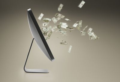 Personal computer en zwevende dollarbiljetten die uit het scherm komen