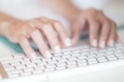 Vrouw aan het typen op wit toetsenbord