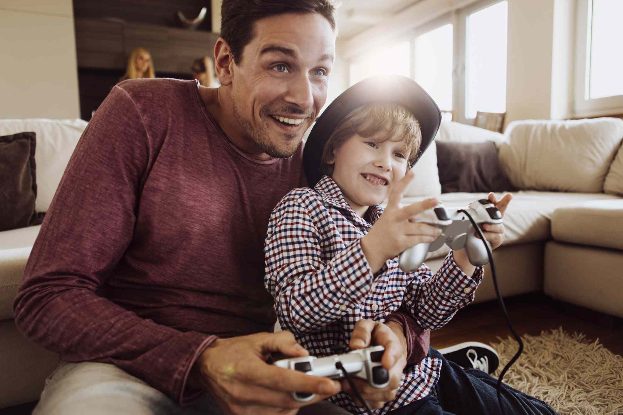 Een ouder en kind spelen samen PlayStation-games op de vloer van de woonkamer. 