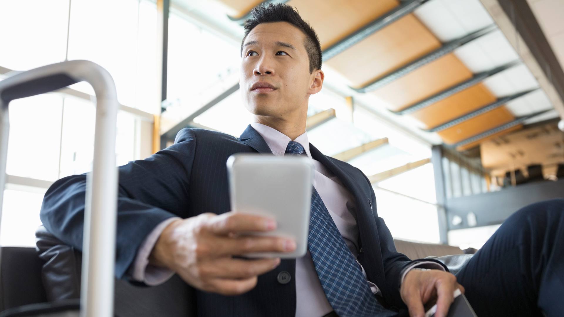 Aziatische zakenman op zakenreis die zijn telefoon controleert met draagbare wifi.