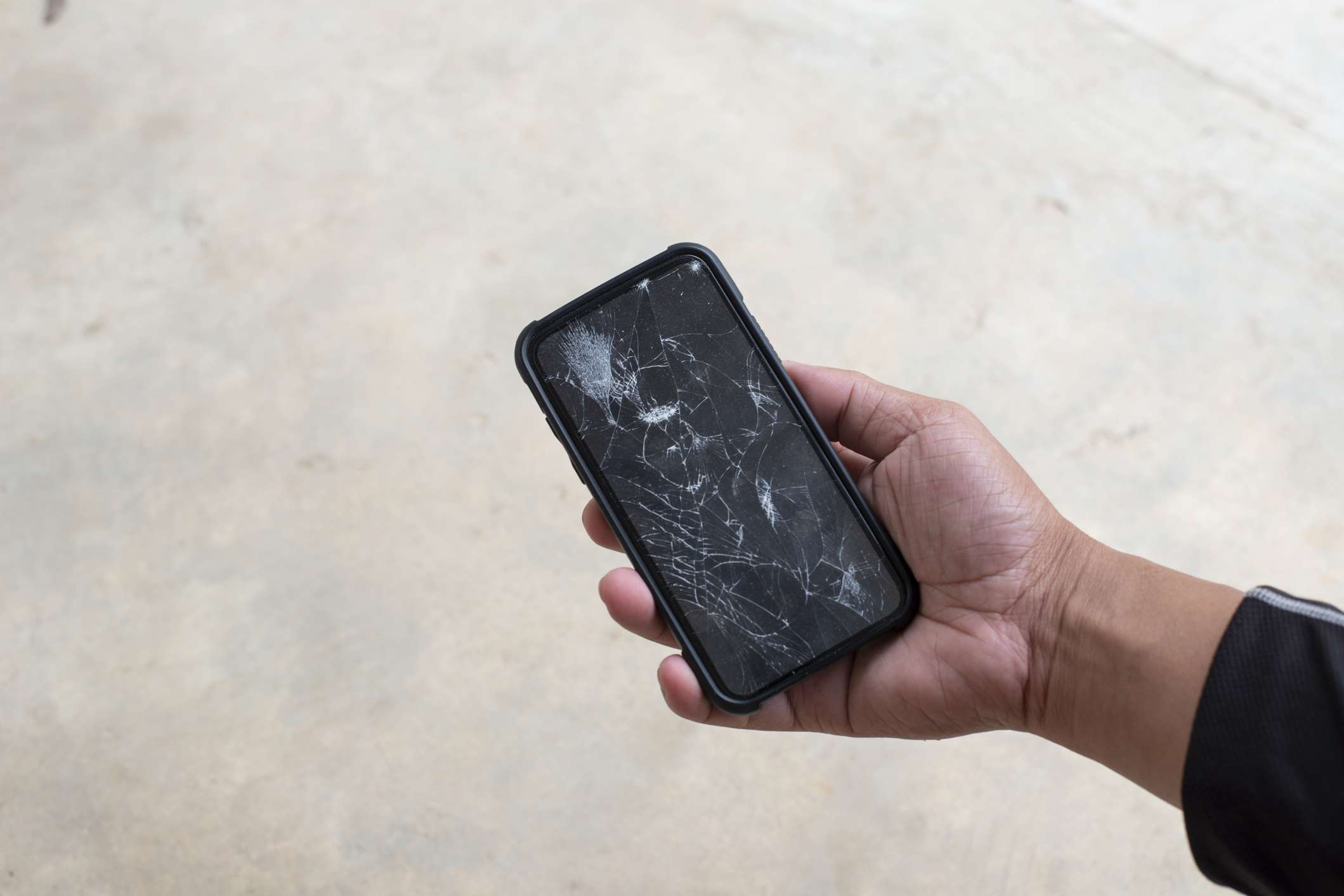 Een hand met een smartphone met een gebroken scherm.