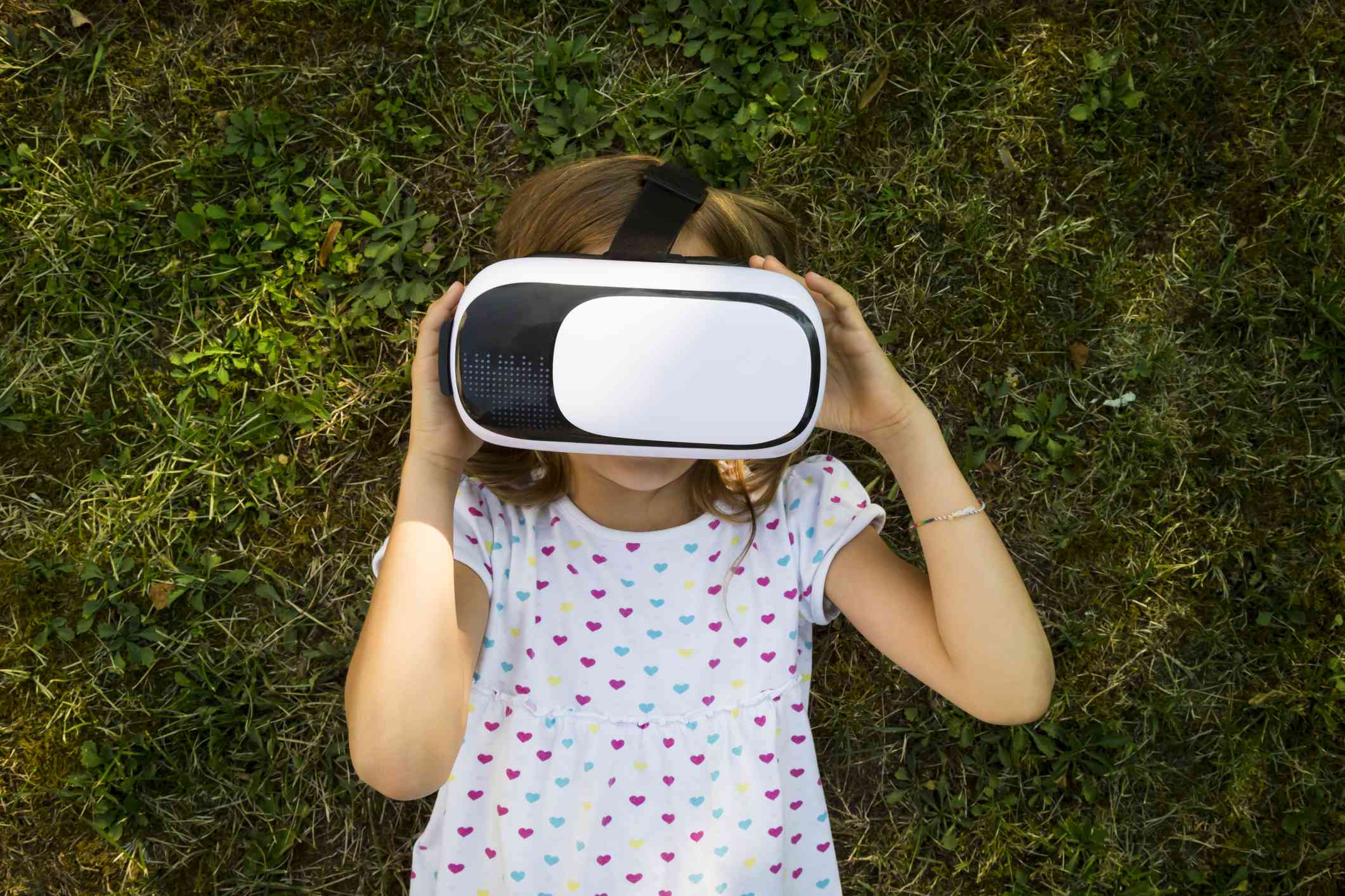 Een kind met een VR-bril op de grond in een tuin. 