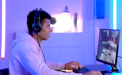 Een man die videogames streamt op Twitch op zijn computer met paarse lichten om hem heen.
